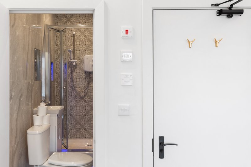 Modern bathroom with toilet, shower enclosure, tiled walls and white fixtures