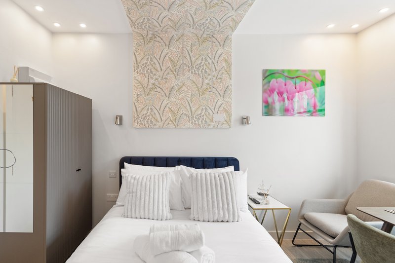 Modern bedroom with double bed, white pillows, wardrobe and decorative wall art