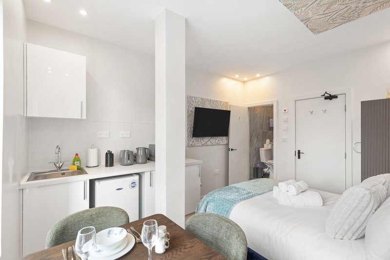 Studio bedroom with kitchenette, dining table, bed, and wall-mounted TV