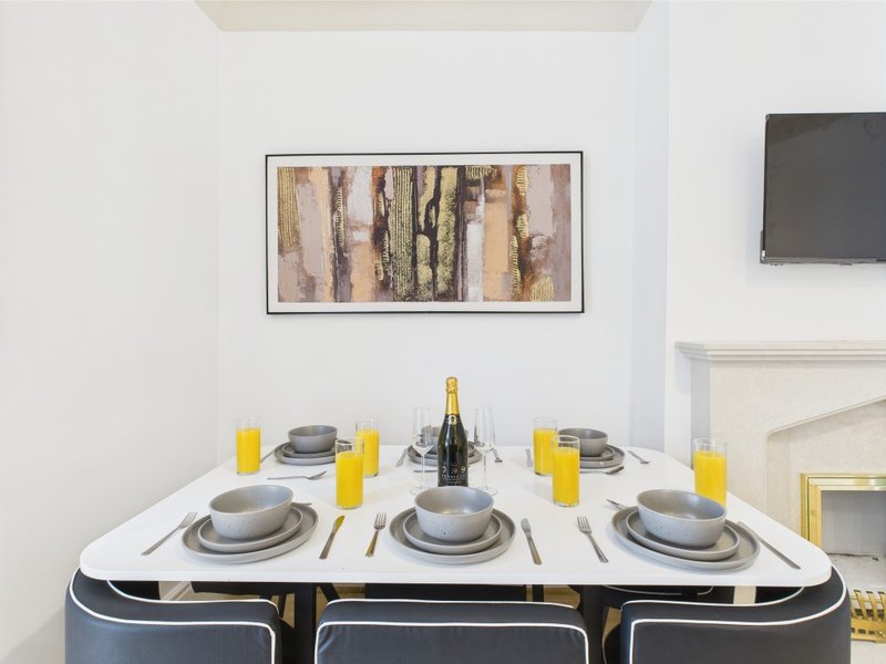 Dining table set for three with champagne bottle, yellow candles, and place settings