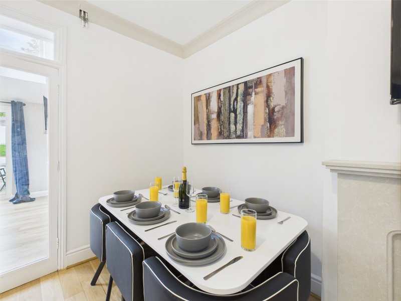 Dining area with set table, black chairs, wine bottle, and framed wall art