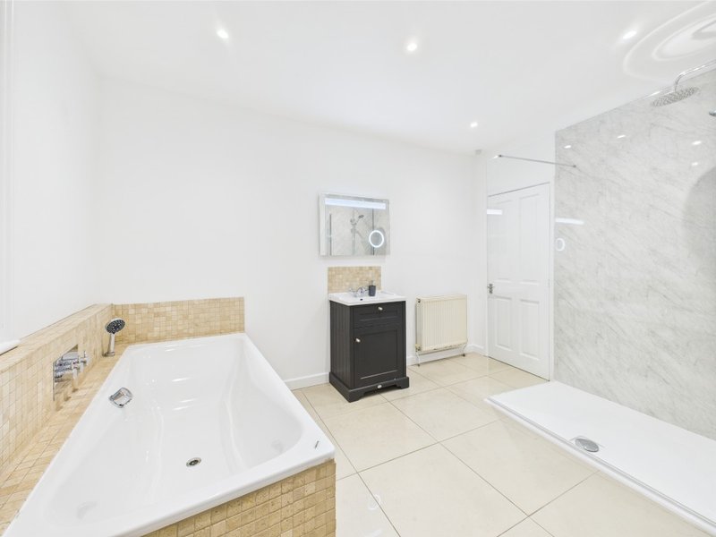 Modern bathroom with white bathtub, walk-in shower, black vanity cabinet and tiled floors
