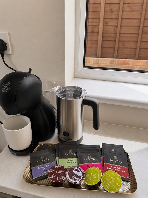 Kitchen counter with coffee maker, milk frother, mugs, and coffee pods by window