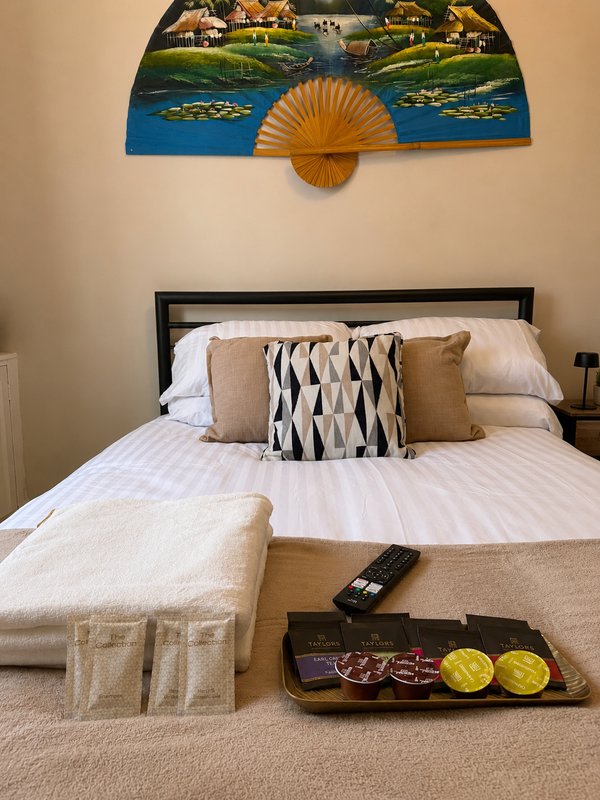 Bedroom with double bed, decorative wall fan, patterned cushions and bedside accessories