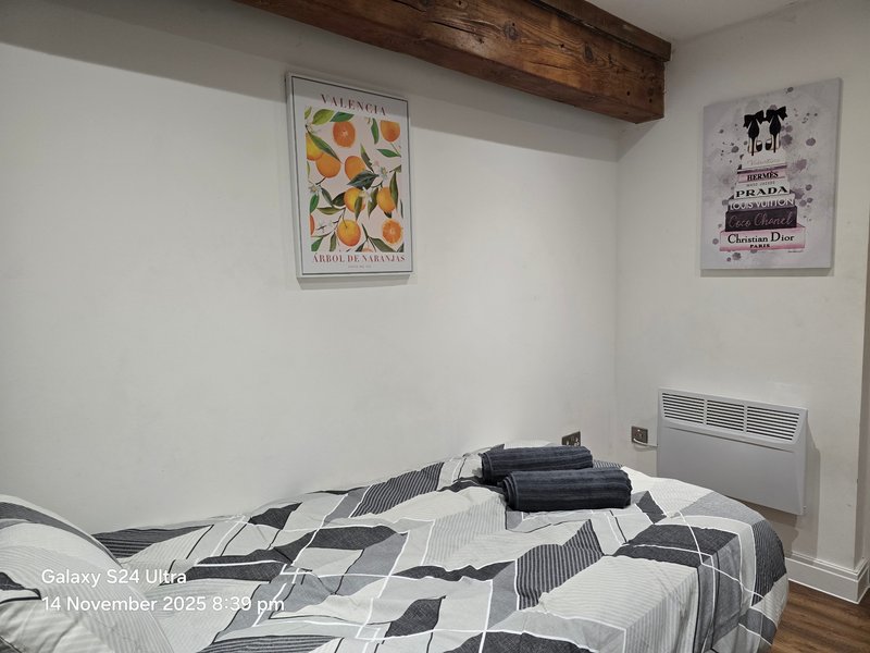 Bedroom with double bed, geometric bedding, wooden beam ceiling and two framed wall prints