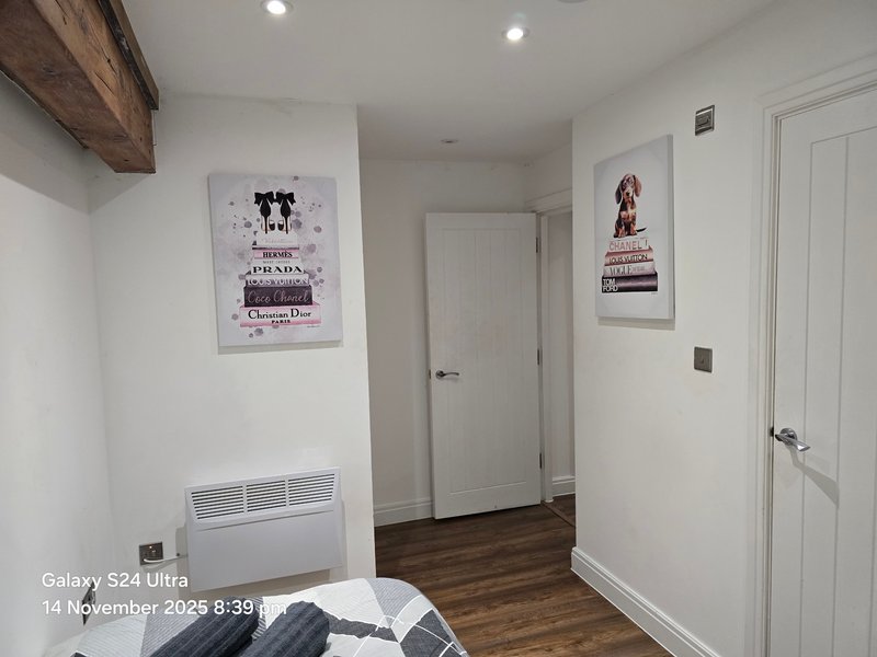 Modern bedroom with white walls, wooden floor, bed, and framed wall art