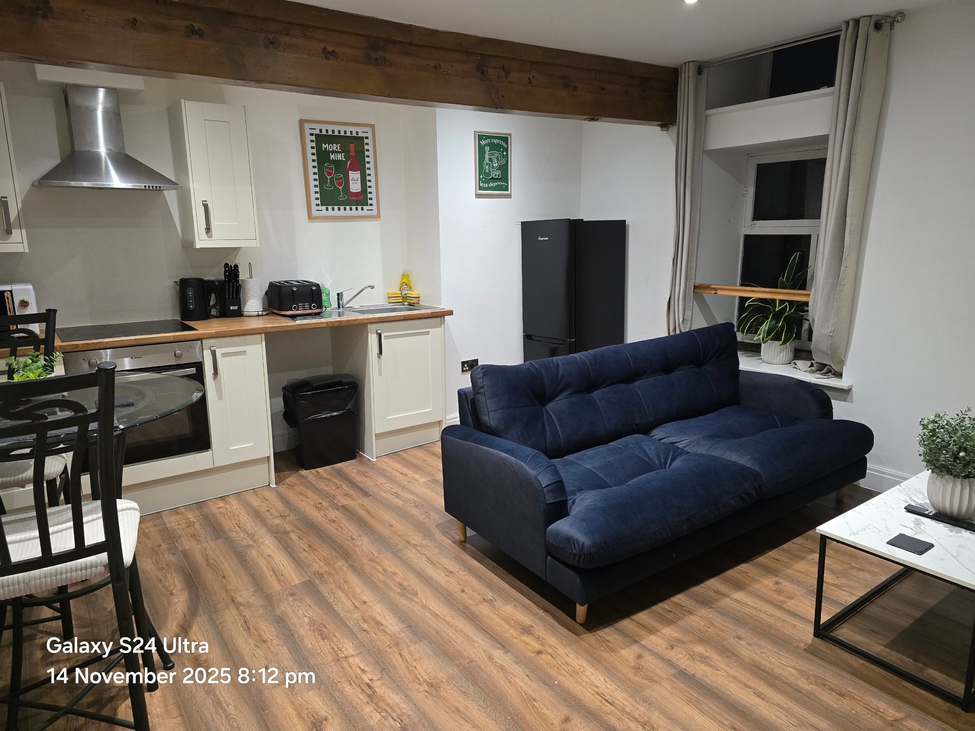 Open-plan living room with kitchen, navy sofa, wooden flooring and dining area