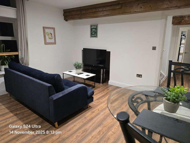 Modern living room with navy blue sofa, TV, wooden beams, and wooden flooring