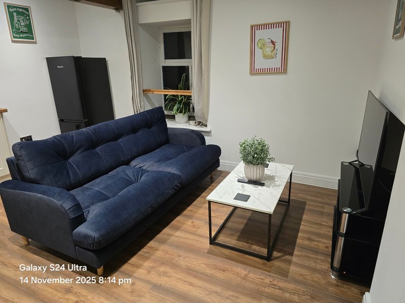 Living room with navy blue sofa, white coffee table, wooden floor and wall art