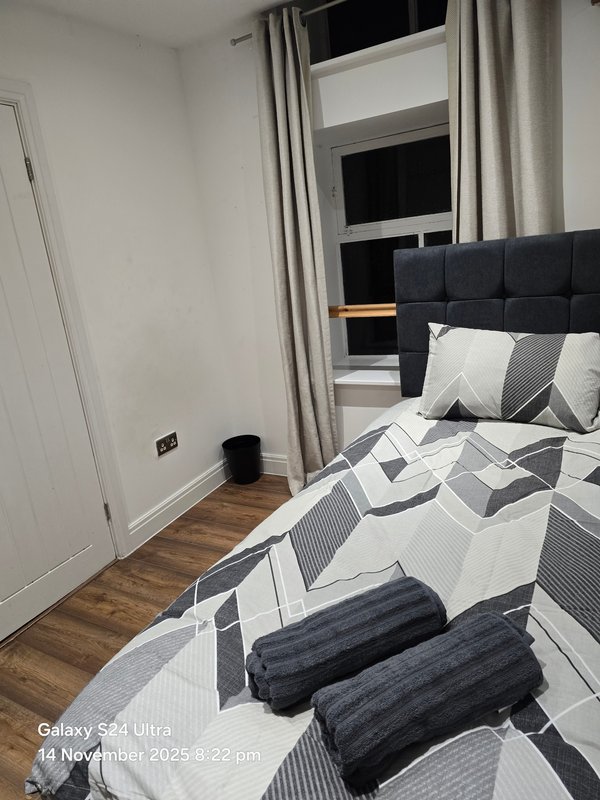Modern bedroom with double bed, geometric bedding, black headboard, and wooden flooring