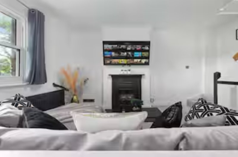 Modern living room with sofa, fireplace, wall-mounted TV, and patterned cushions