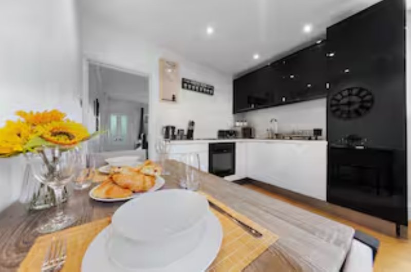 Modern kitchen with dining table, yellow flowers, black cabinetry and white countertops