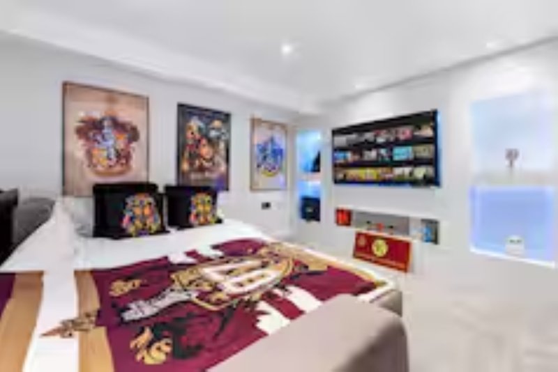 Bright bedroom with double bed, purple rug, wall art, TV, and large window with city view