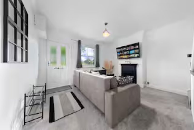 Open-plan living room with grey sofa, fireplace, kitchen area and pendant lighting