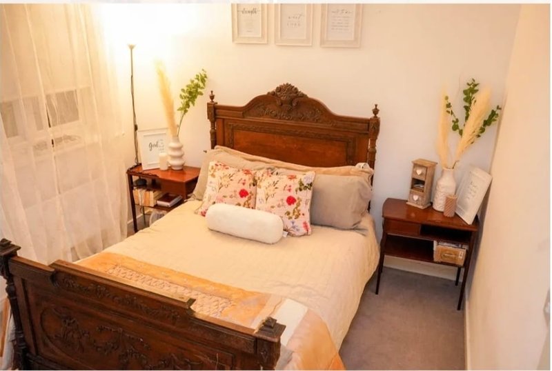 Traditional bedroom with wooden bed frame, cream bedding, floral cushions and bedside tables