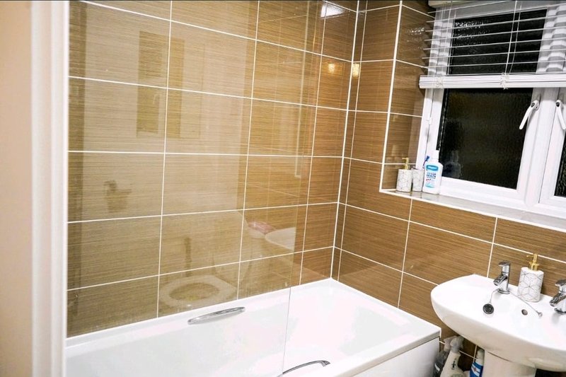 Modern bathroom with walk-in shower enclosure, bathtub, white sink and tan tile walls