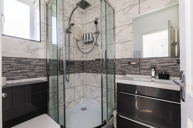 Modern bathroom with walk-in shower, marble tiles, black vanity unit and mirror