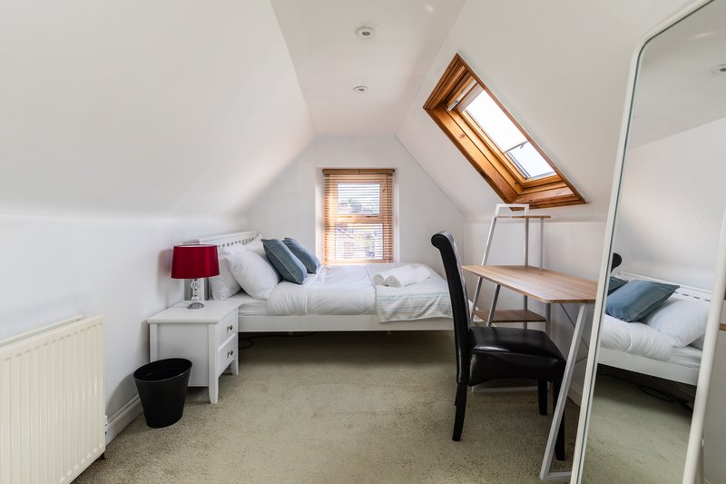 Bright attic bedroom with two single beds, skylight window, and wooden furniture