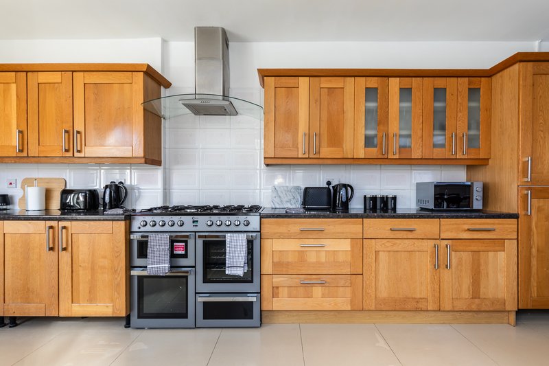 Modern kitchen with wooden cabinets, dual ovens, range hood and stainless steel appliances