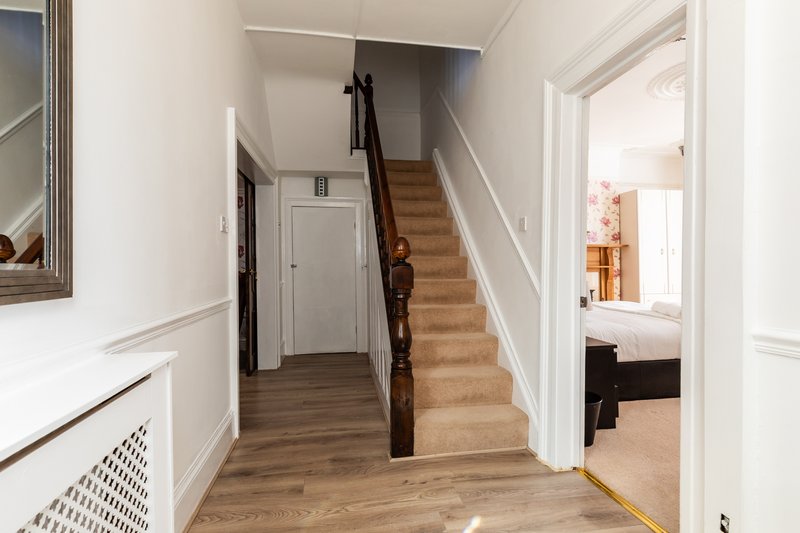 Hallway with wooden staircase, white walls, wood flooring and bedroom view