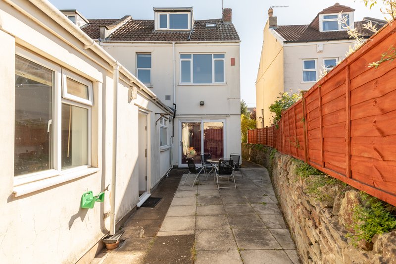 Patio area with paving, garden furniture, white conservatory and orange wooden fence