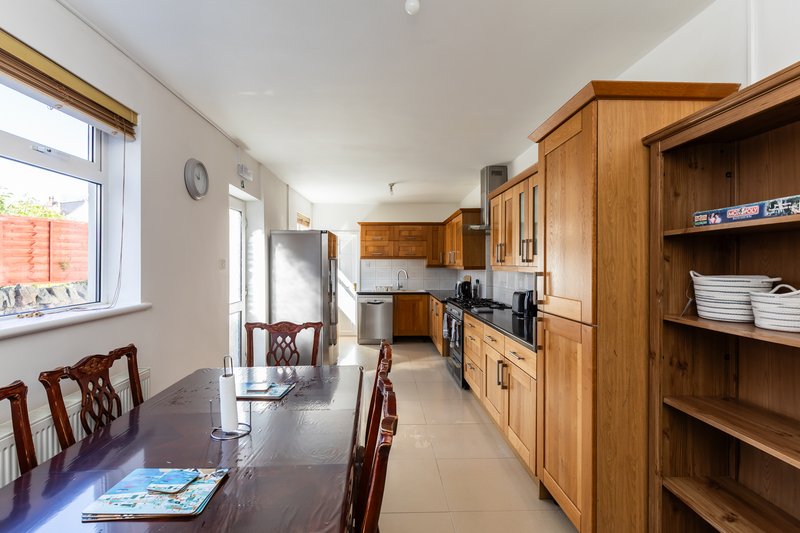 Kitchen-diner with wooden cabinetry, dining table, chairs, and garden view through window