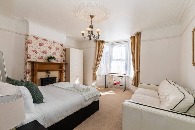 Spacious bedroom with double bed, fireplace, bay window, and seating area