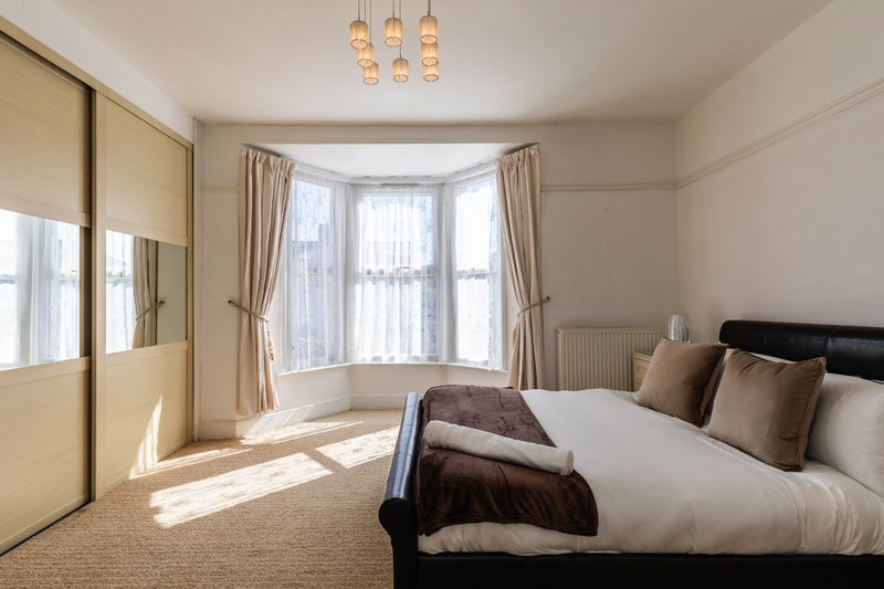 Bright modern bedroom with double bed, bay window, sliding wardrobe and pendant lighting