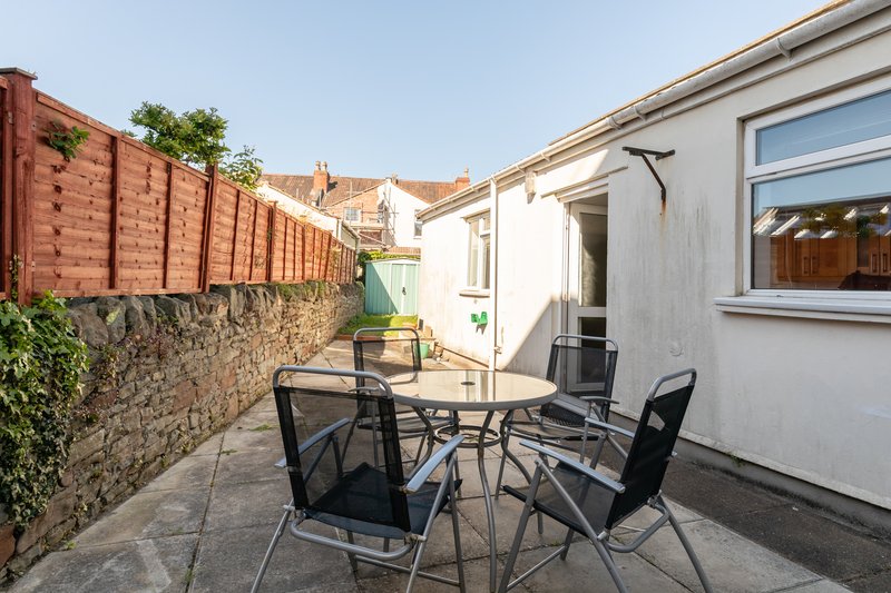 Patio area with dining table, four chairs, brick wall and garden beyond