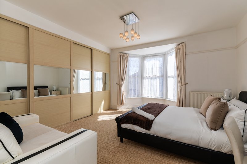 Spacious bedroom with double bed, built-in wardrobe, bay window and ceiling light fixture