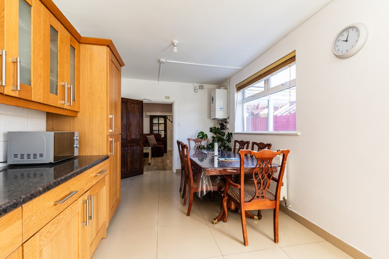 Kitchen and dining area with wooden cabinets, dining table, chairs and clock on wall