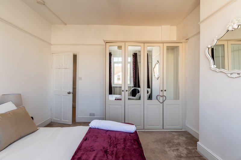 Bedroom with double bed, burgundy throw, wardrobe doors and mirror