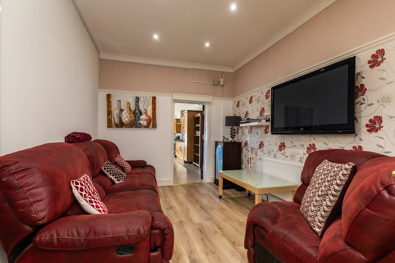 Living room with red leather recliners, wall-mounted TV, and floral wall decor