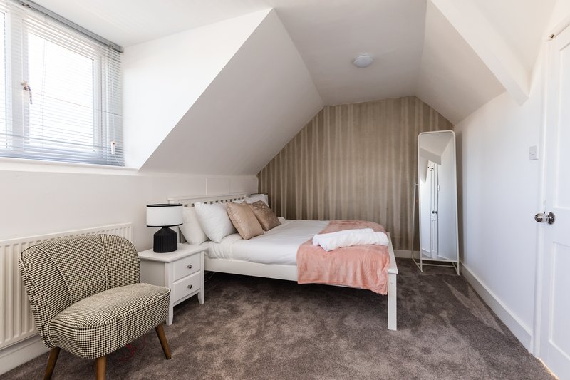 Attic bedroom with single bed, upholstered chair, wardrobe and sloped ceiling