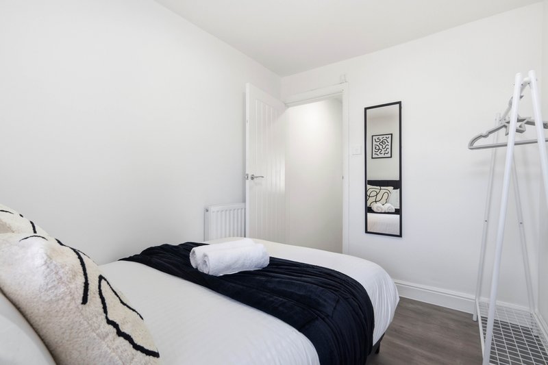 Bright bedroom with single bed, white bedding, dark throw, and minimalist wall decor