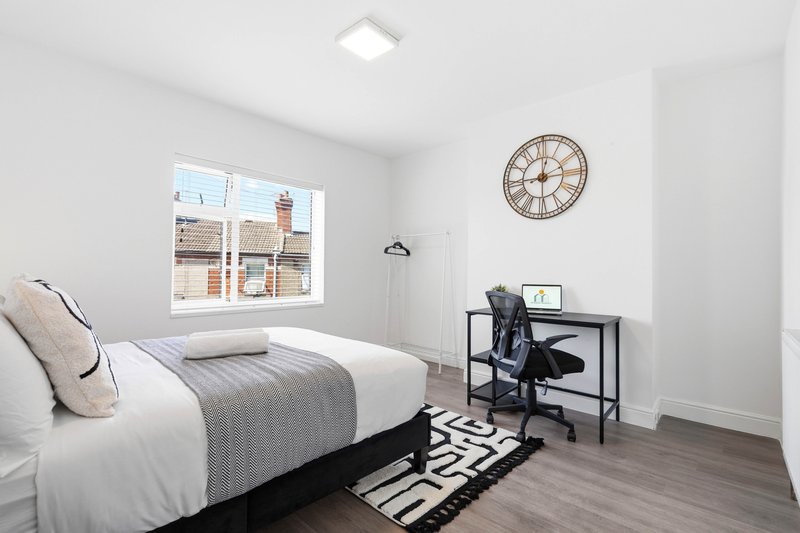 Modern bedroom with double bed, desk, wall clock and large window