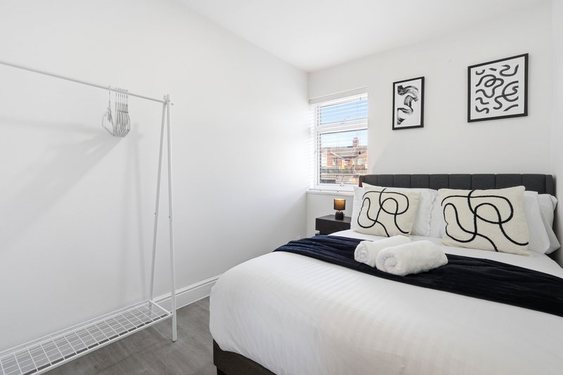 Modern bedroom with double bed, black headboard, white bedding, abstract wall art and window