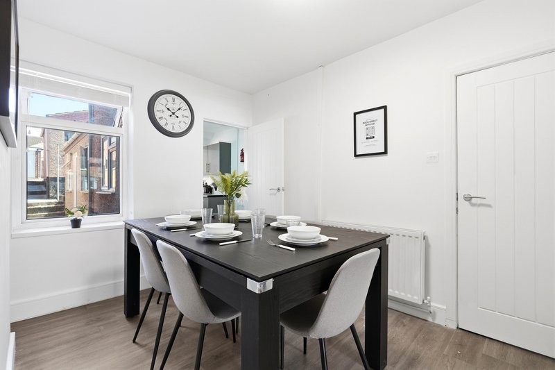 Modern dining room with black table, grey chairs, wall clock and window view