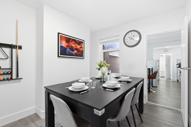 Modern dining room with black table, white chairs, wall art and wall clock