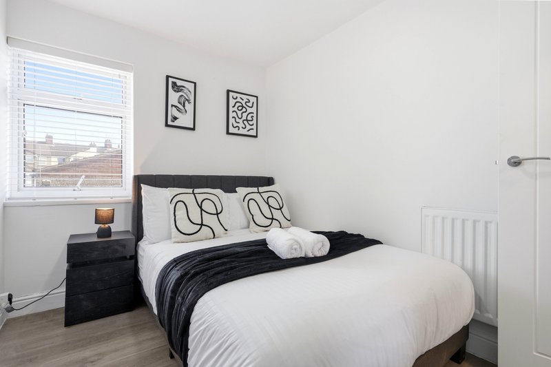 Modern bedroom with double bed, black headboard, white bedding and patterned pillows