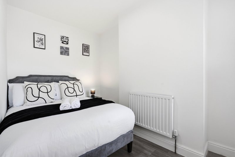 Modern bedroom with double bed, black headboard, patterned cushions and white radiator