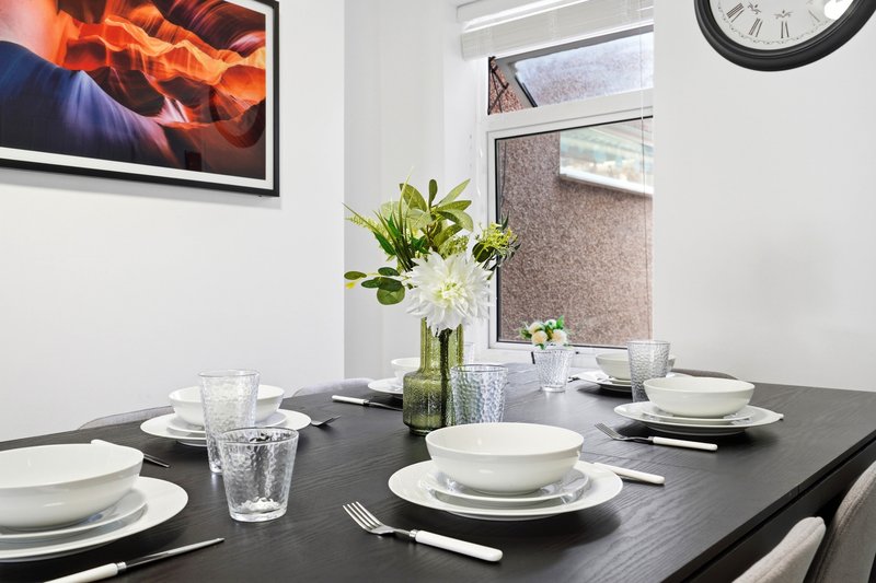 Dining table set for four with place settings, flowers, and wall art