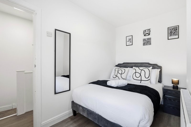 Modern bedroom with double bed, black and white bedding, framed wall art, and wooden flooring