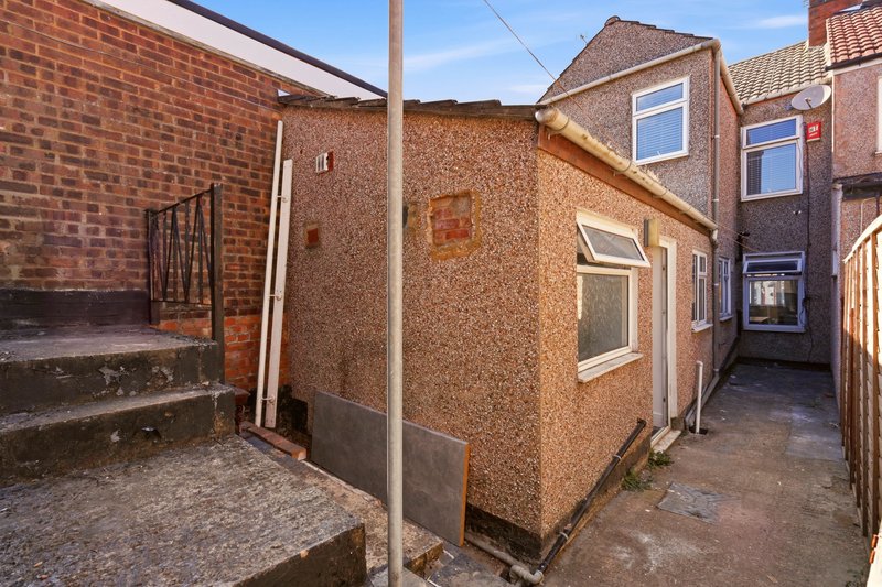 Exterior view of brick and rendered residential building with paved courtyard and alleyway