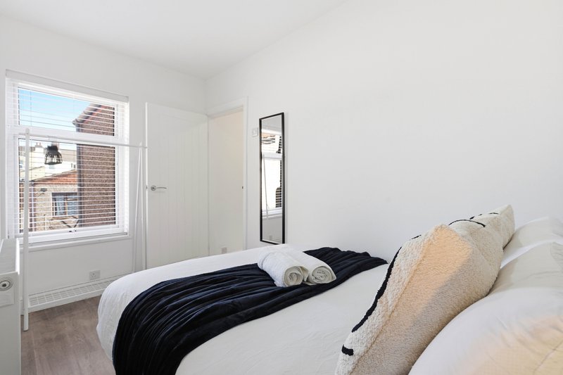 Modern bedroom with double bed, rolled towels, cushions, window with brick view and mirror