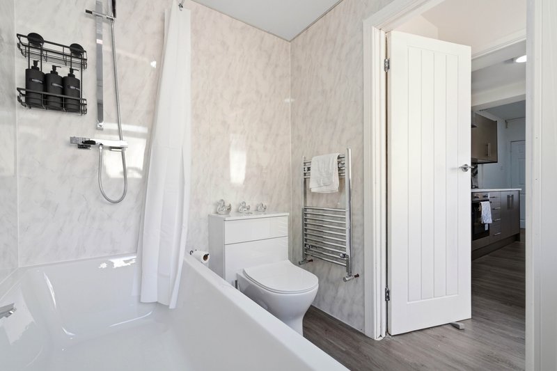 Modern bathroom with white suite, shower cubicle, heated towel rail and tiled walls