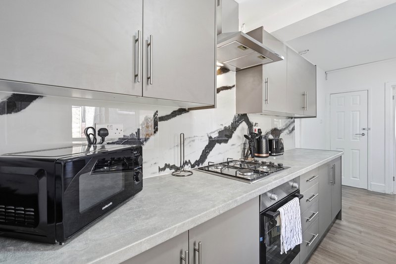 Modern kitchen with white cabinetry, grey countertops, black appliances and island