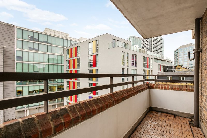 Balcony with brick wall overlooking modern residential buildings with colorful facades