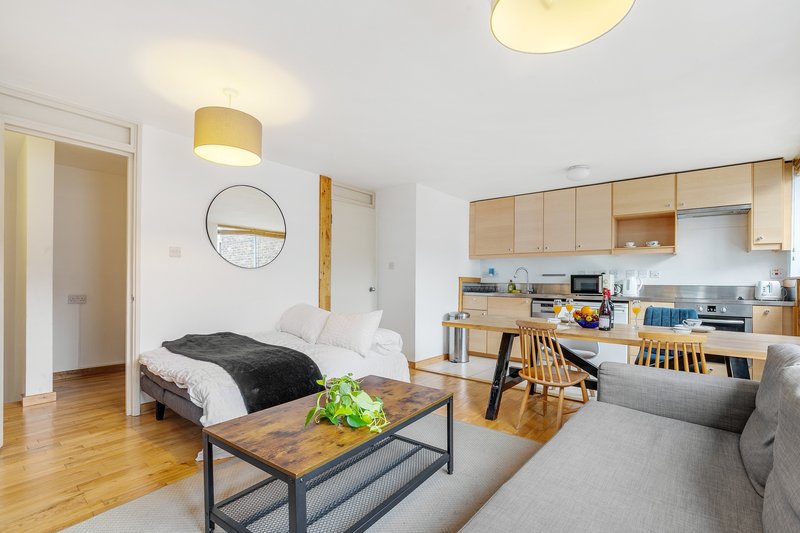 Open-plan studio apartment with bed, sofa, kitchenette and wooden flooring throughout