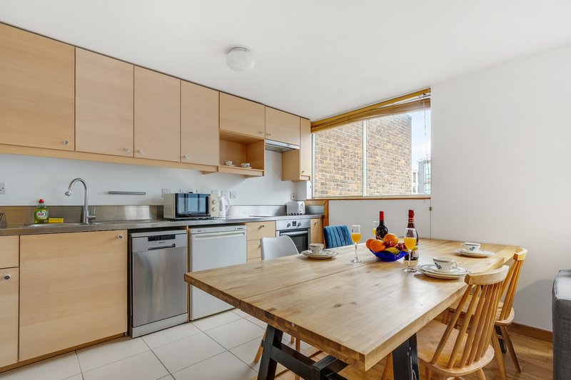 Modern kitchen with wooden cabinets, dining table, and stainless steel appliances